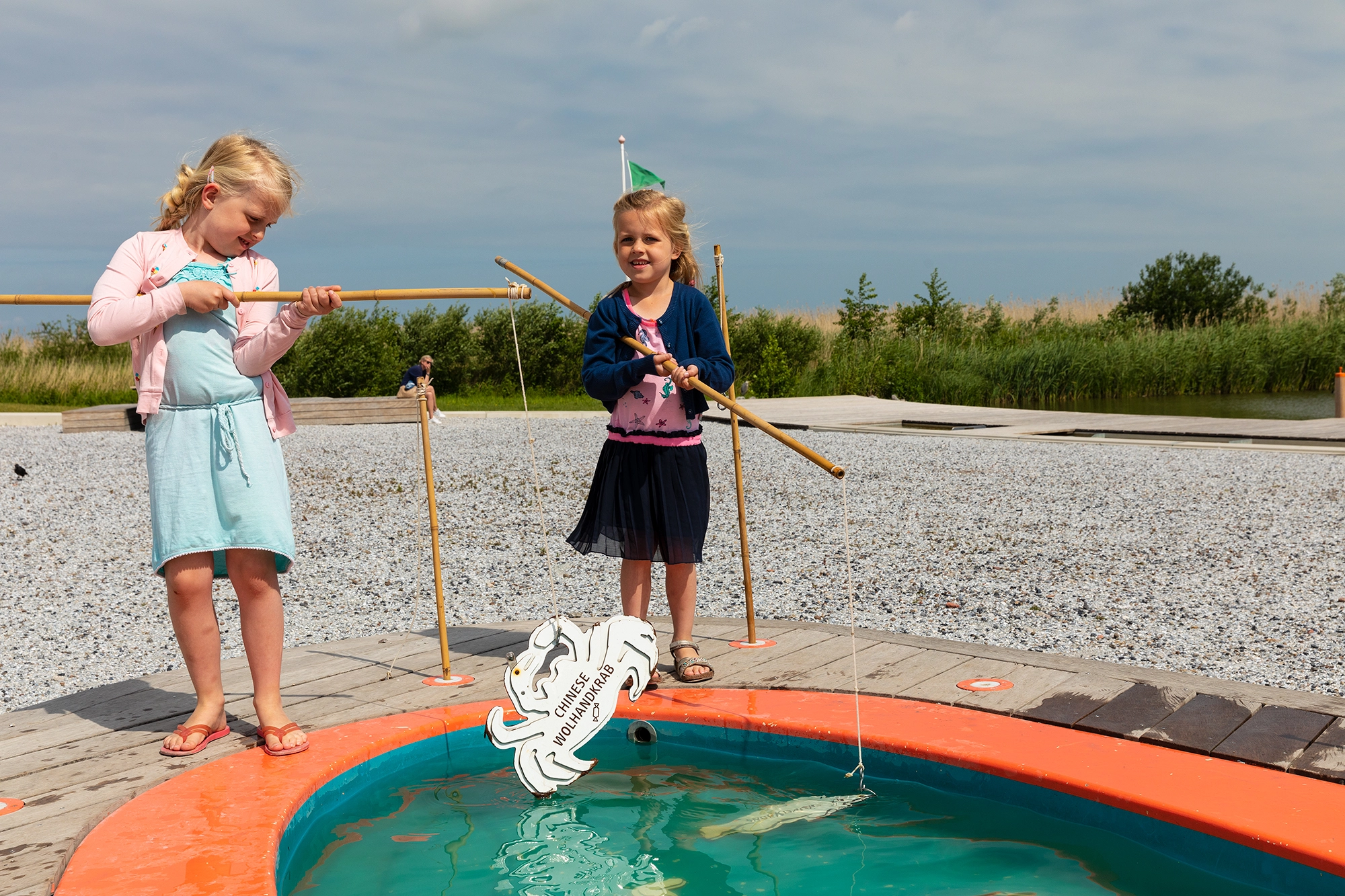 Twee kinderen vissen met hengels in een klein zwembad als onderdeel van een interactieve wateractiviteit.